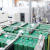 PCB Panels In Antistatic Rack On High Speed SMT Assembly Line Stacked PCB panels in an ESD rack with technician and SMT equipment in the background on a modern automated electronics production line