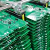 Stack Of Assembled Circuit Boards In Metal Rack At Modern Electronics Factory Close view of assembled green circuit boards stacked in adjustable rack inside modern automated electronics manufacturing plant